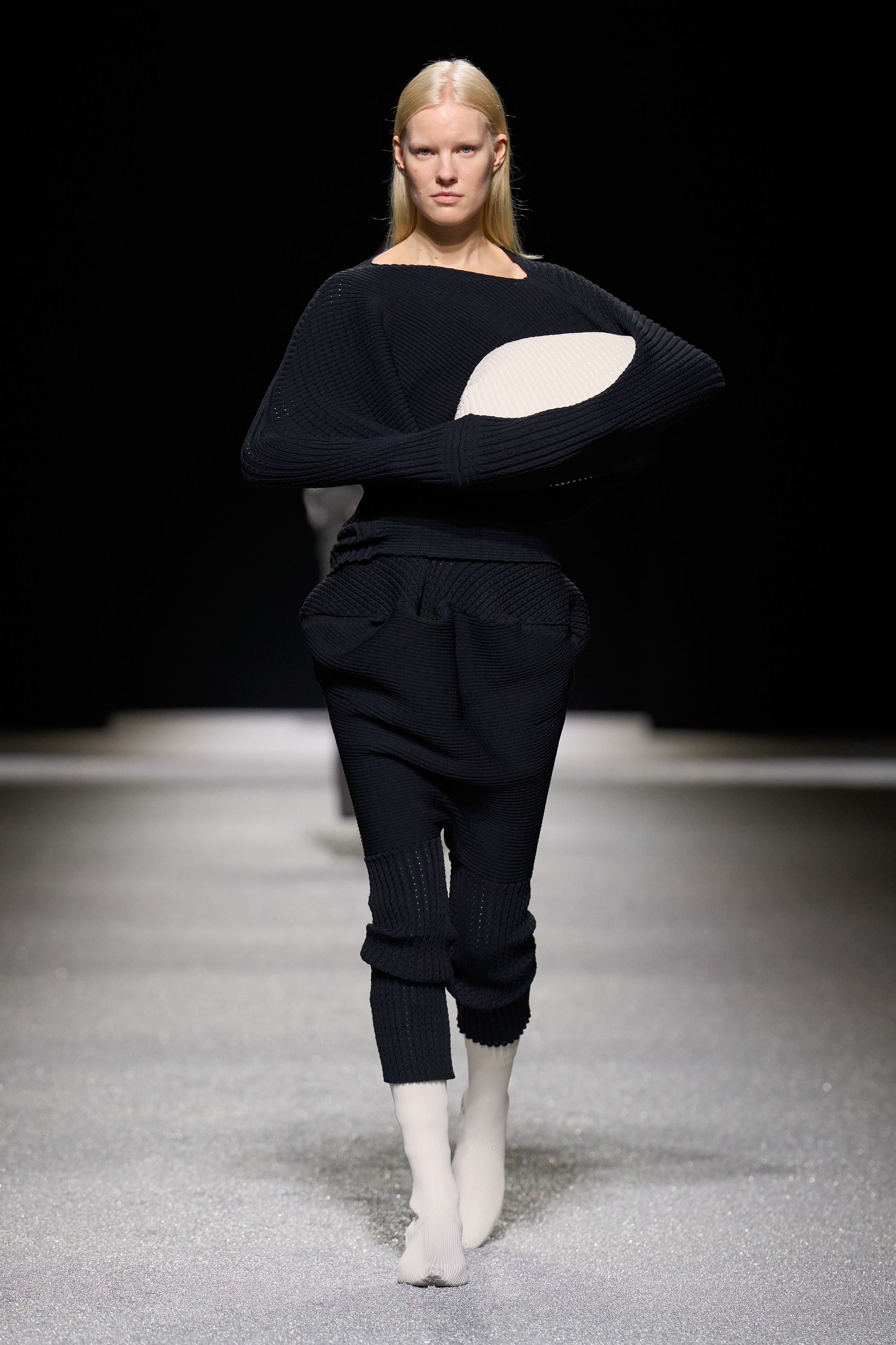Issey Miyake 这一季把“留白”做成了真正可被看见的力量：黑白灰的大面积静默、宽松针织与褶皱结构先建立禅意秩序，随后以明黄、亮粉与雕塑化体量突然打破沉静，让衣服像在呼吸，也像在生长。它不是简单的极简主义，而是一种把工艺、身体与空间关系重新推向前台的诗性实验-顽石频道趋势研究
